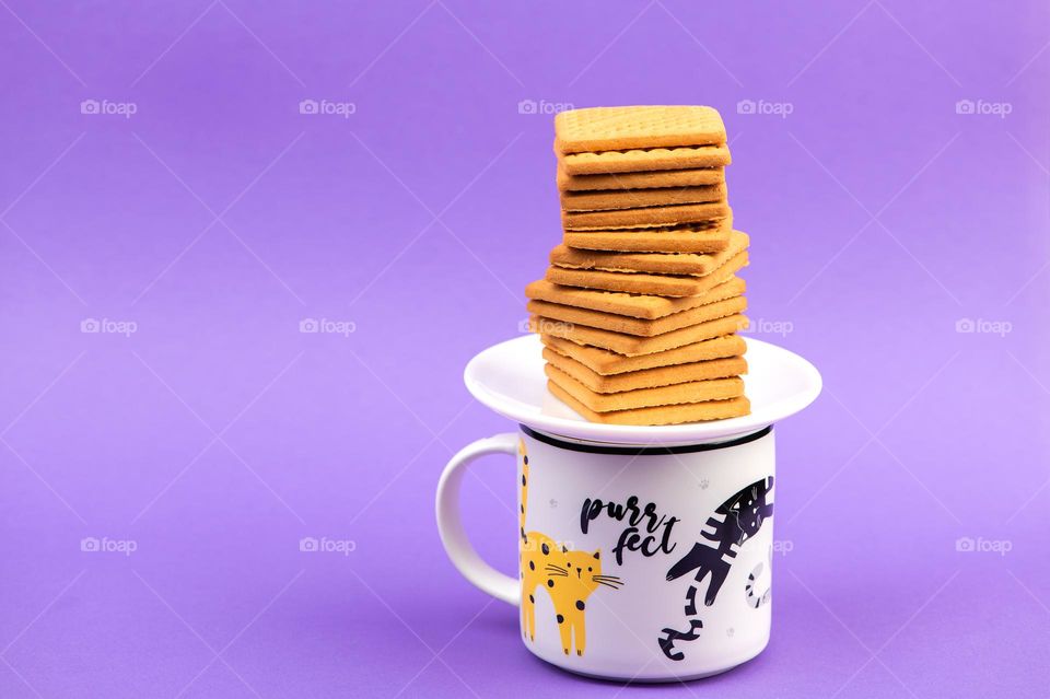 Square biscuits on stylish cup on purple