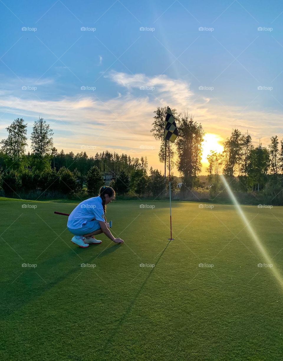 girl on the golf course playing at sunset, summer time