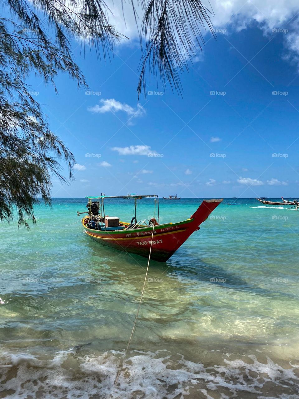 Beautiful crystal clear ocean with long tail boat parked on the beach.