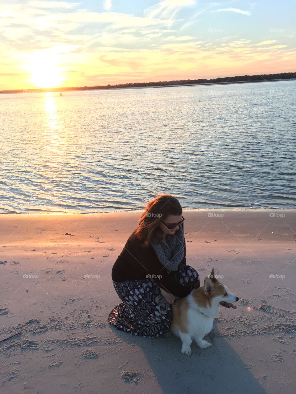 Woman with her dog at beach during sunset