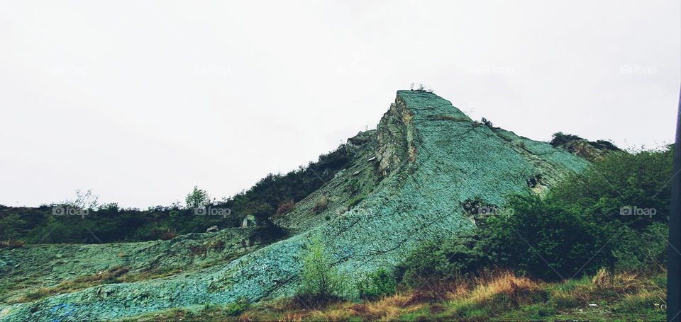 The image shows green volcanic tuff, a rock formed from consolidated ash, with its color resulting from mineral alterations. It is a feature of areas with past volcanic activity.