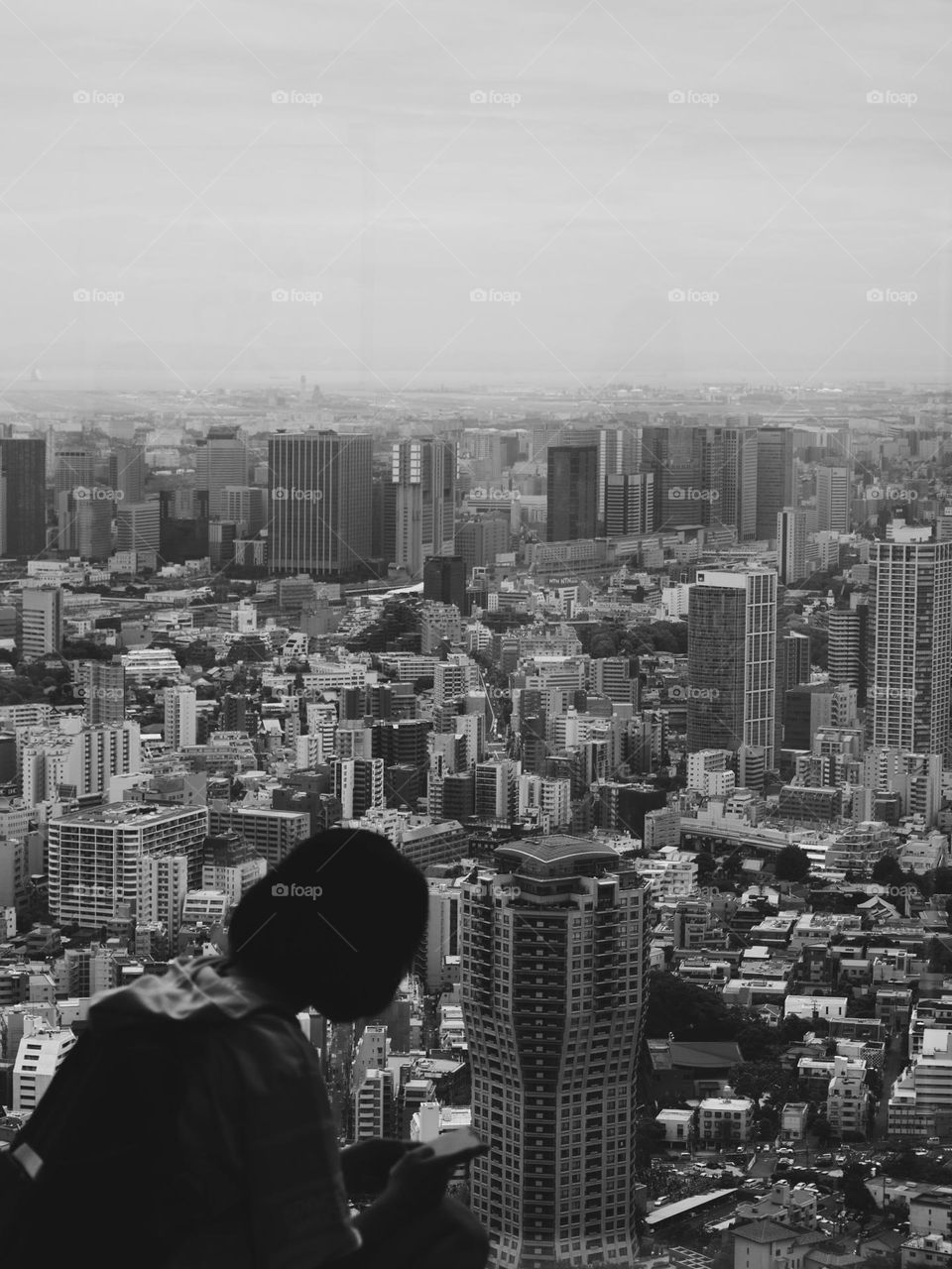 Japanese girl sitting by the window, looking at her phone 