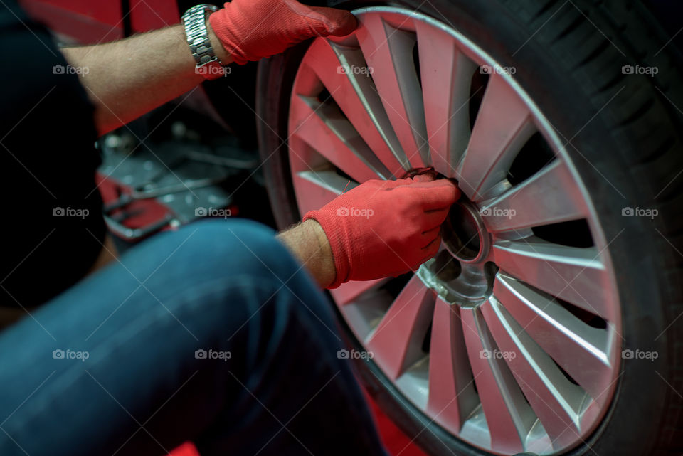 Mechanician changing car wheel in auto repair shop