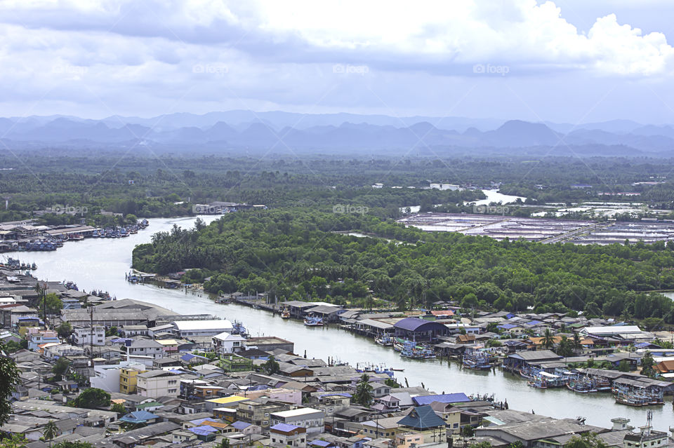 The point of view of Cityscape and a boat parked in Tha Taphao river , Background mountains and  sky at Mutsea Mountain Viewpoint in Chumphon , Thailand.