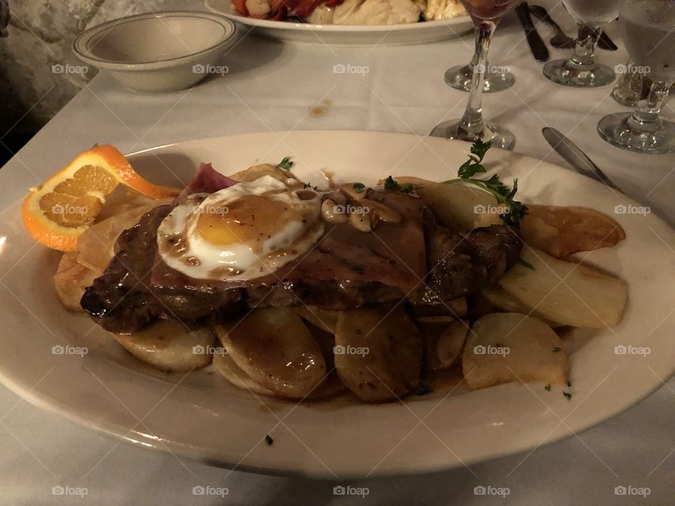 Portuguese sirloin steak with ham, an egg, and potatoes