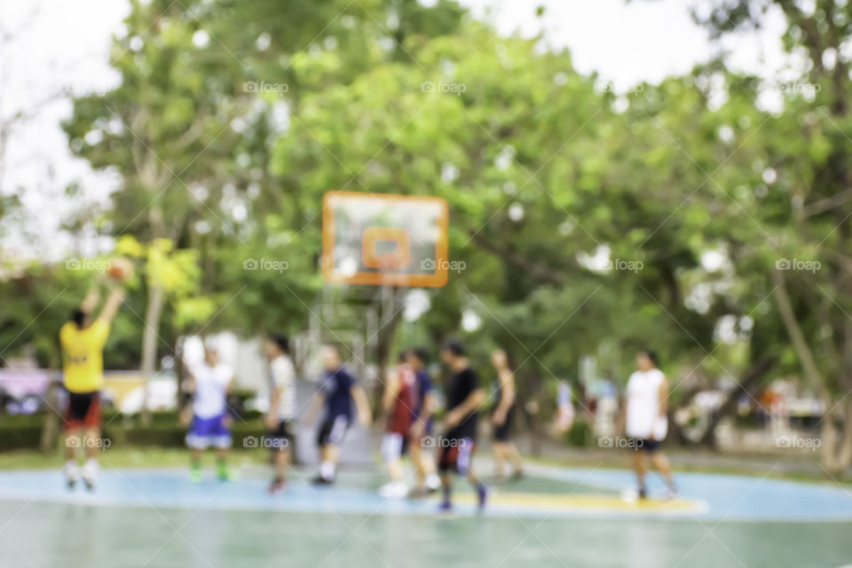 Blurry image of elderly men and teens playing basketball in the morning at BangYai Park , Nonthaburi in Thailand.