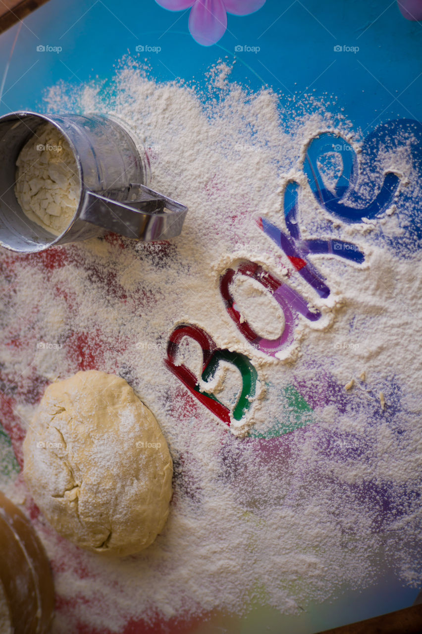 On the table lies a pastry for pies with sprinkled flour and a seeder for flour. Written to bake on the table.