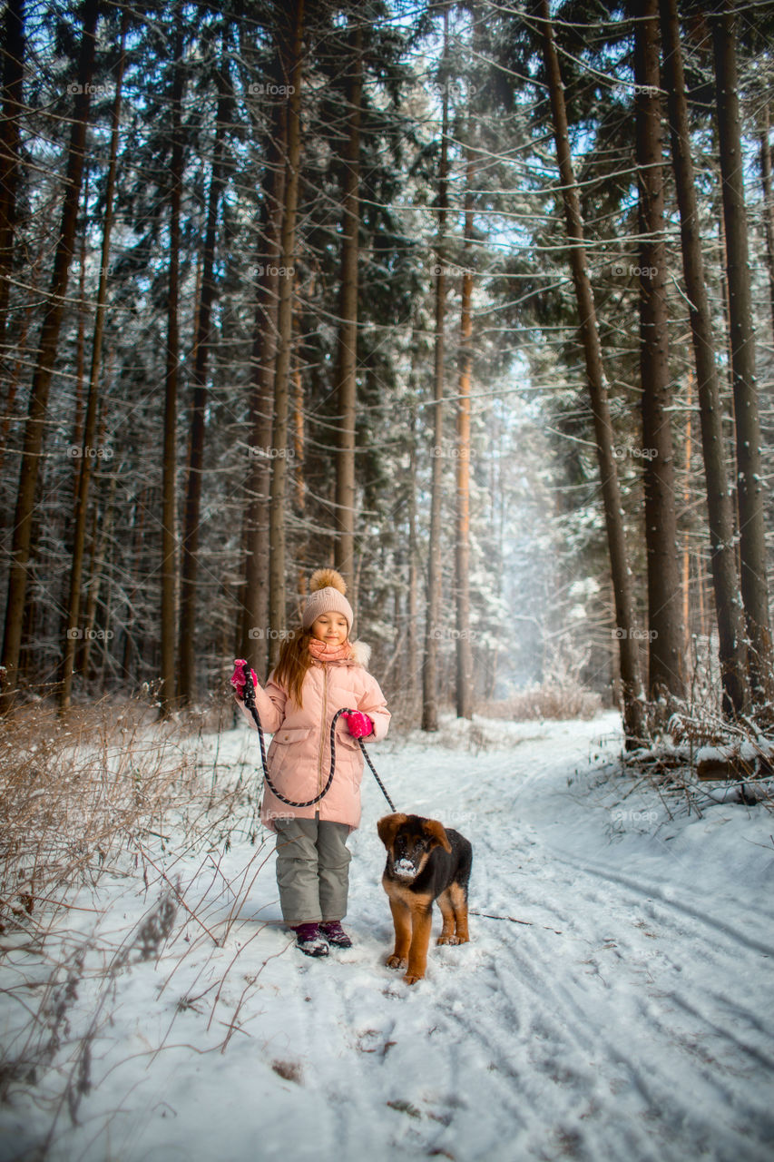 Little girl with German shepherd puppy in a winter park 