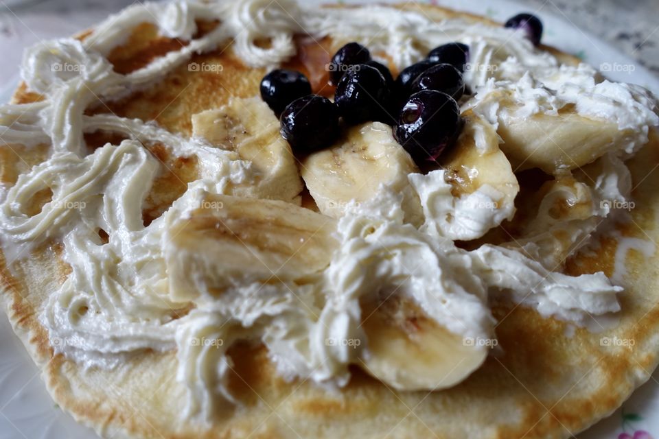 Pancake with banana,blueberries and whipped cream.