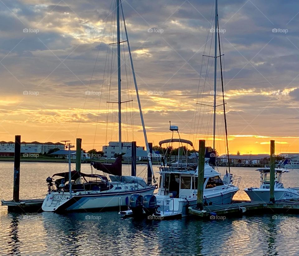 Two sailboats docked at sunset 