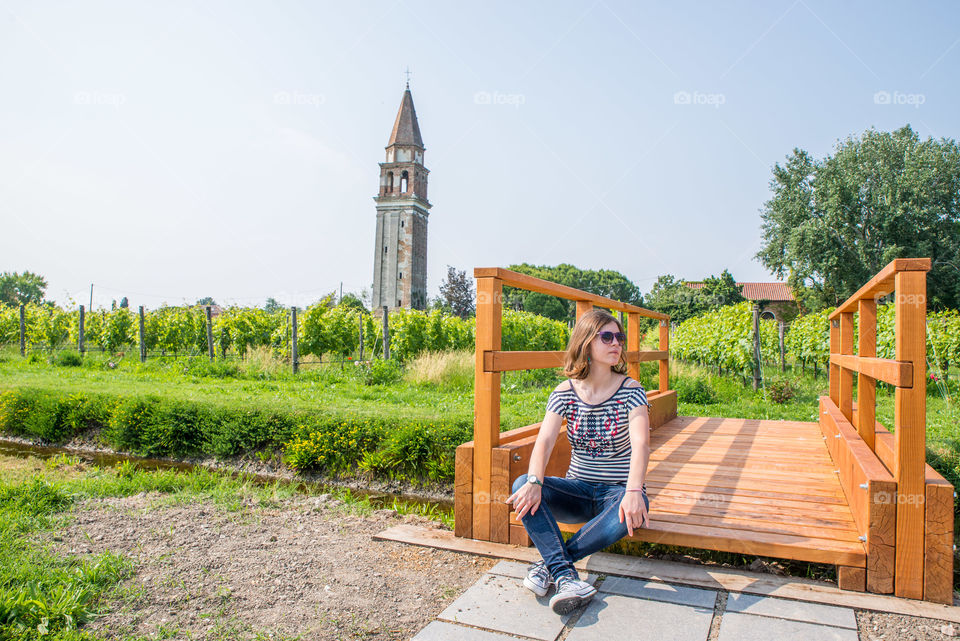 Young woman sitting on wooden bridge