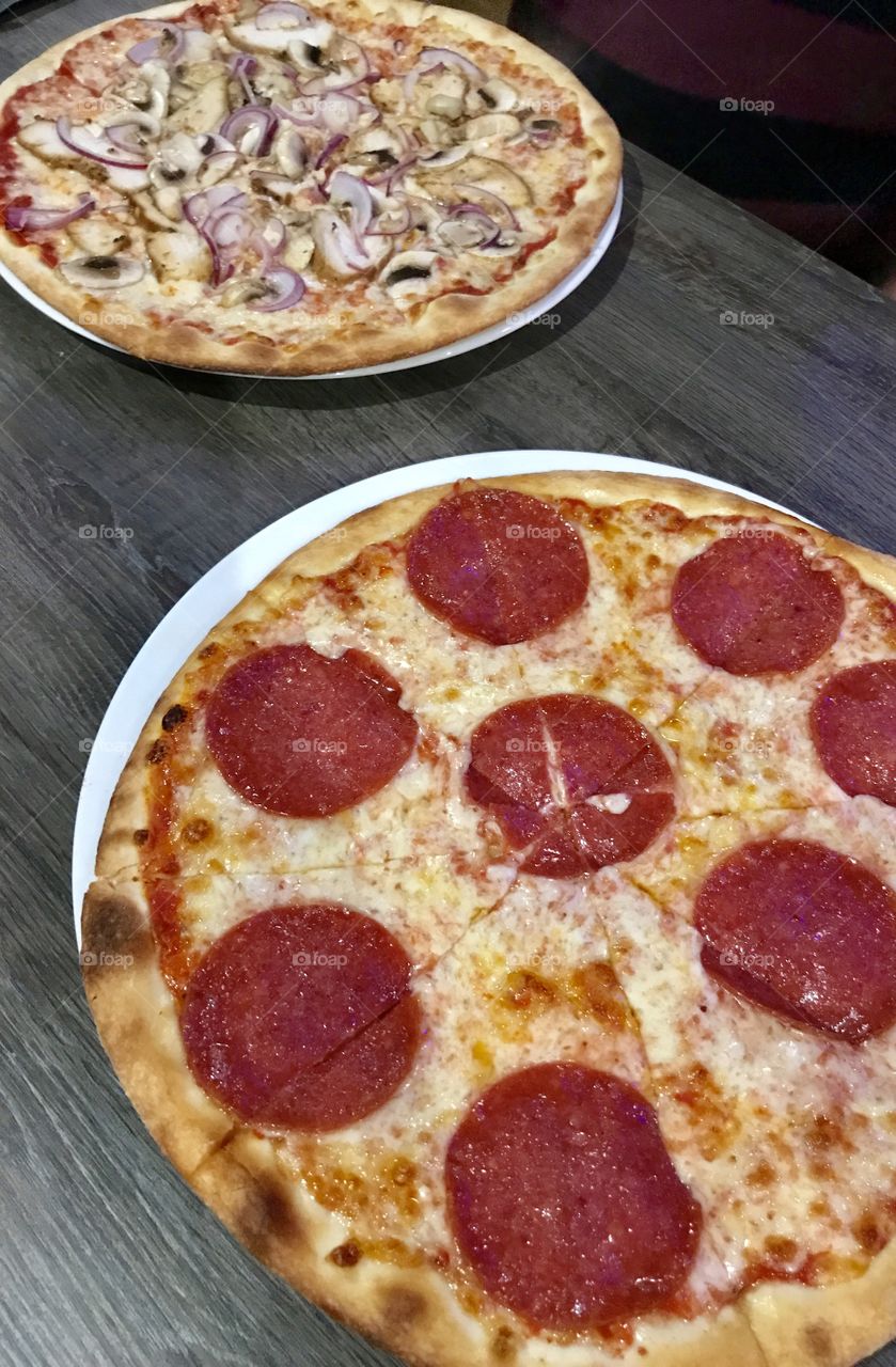 Pizza with salami and pizza with chicken and mushrooms, dark wooden table 