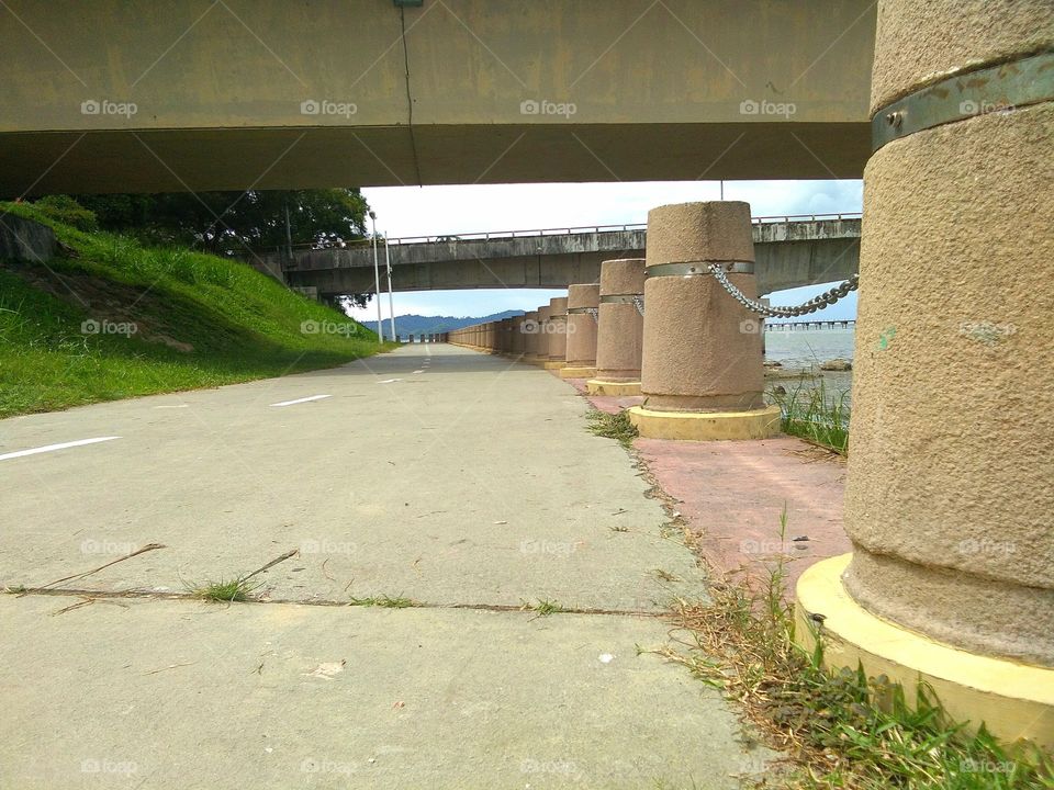 A sidewalk (American English) or pavement(British English), also known as a footpath or footway, is a path along the side of a road. A sidewalk may accommodate moderate changes in grade (height) and is normally separated from the vehicular section by a curb. There may also be a median strip or road verge (a strip of vegetation, grass or bushes or trees or a combination of these) either between the sidewalk and the roadwayor between the sidewalk and the boundary.