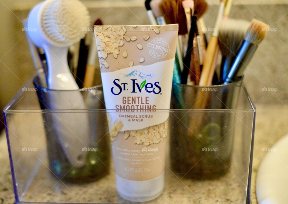 Oil free,gentle smoothing,St Ives scrub and mask in a container on a bathroom counter with brushes in the background 