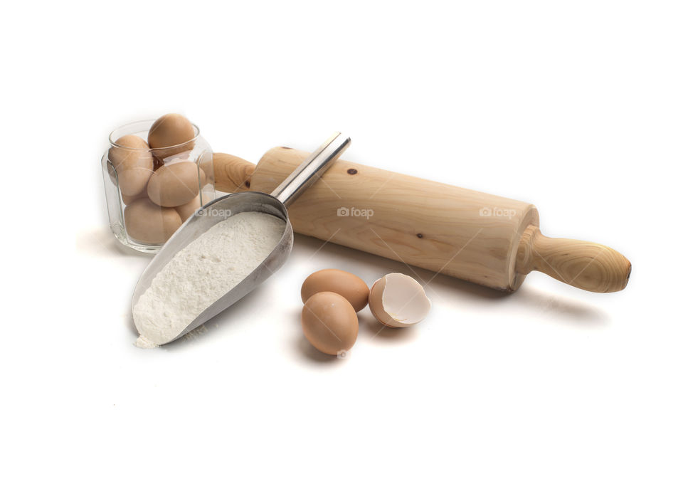 Composition of flour, eggs and a molder on white background