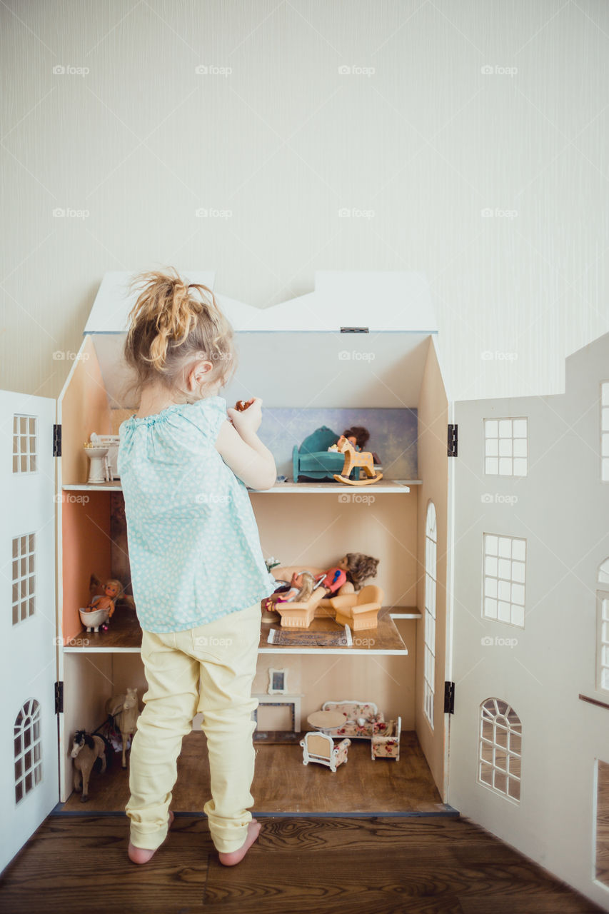 Little girl playing with dollhouse 