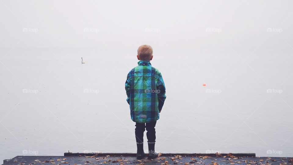 Boy looking over a misty lake