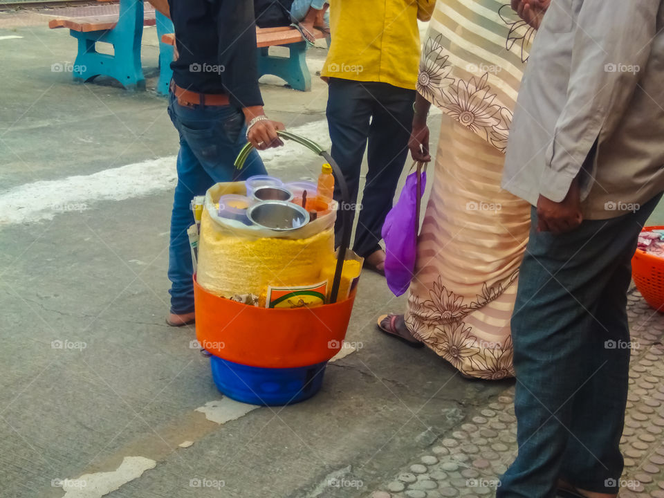 Street food in India - a man selling food named bhel on train platform.