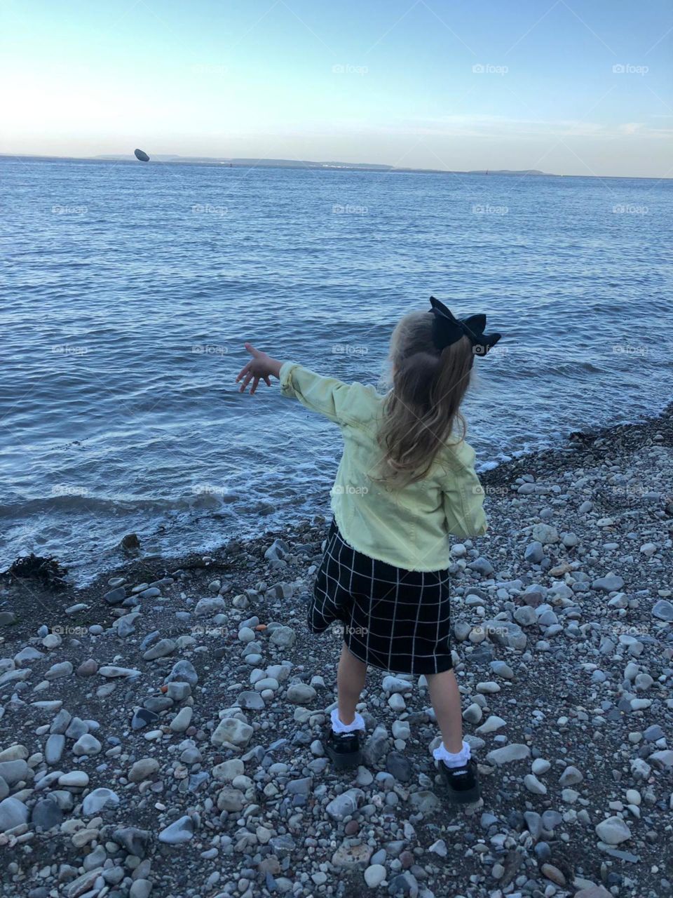 Girl throwing a pebble into the water 