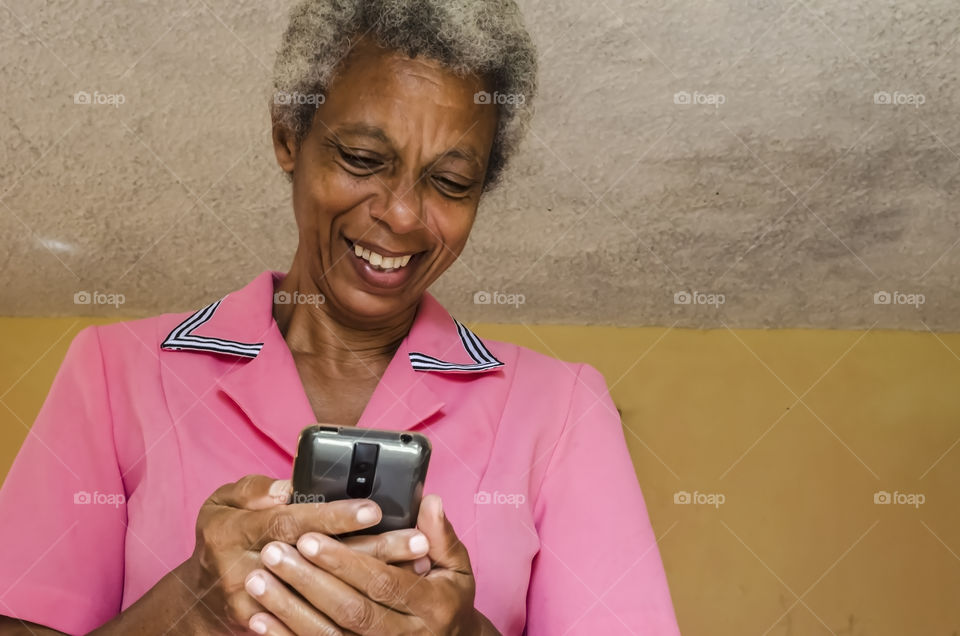 A Senior Woman Smiling As She Reads From Her Mobile Phone