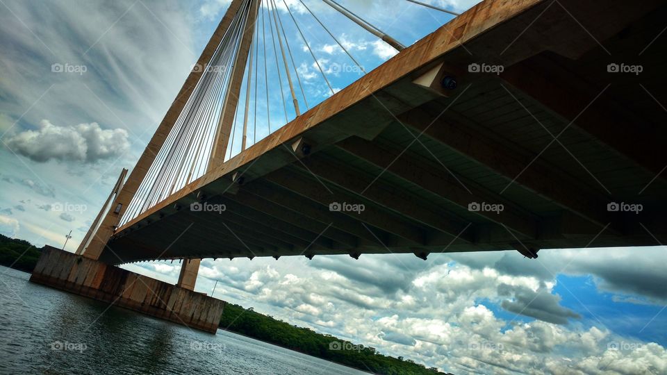 Ponte sobre um rio, suspensa, de concreto e cabos. Divisa de Estados. MS e MG, Brasil.