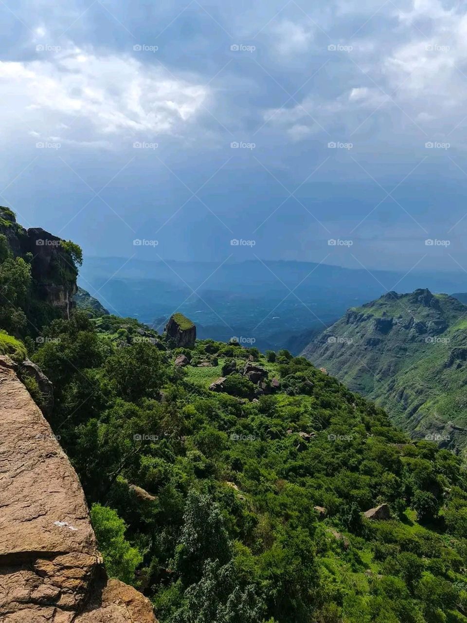 The image embodies a natural natural plate of the mountains of nature, where green agricultural stands are graded on the slopes as if they were lines of a poem, which fog harmoniously wrapped, and clouds hugged them in the mountain knife and the whis