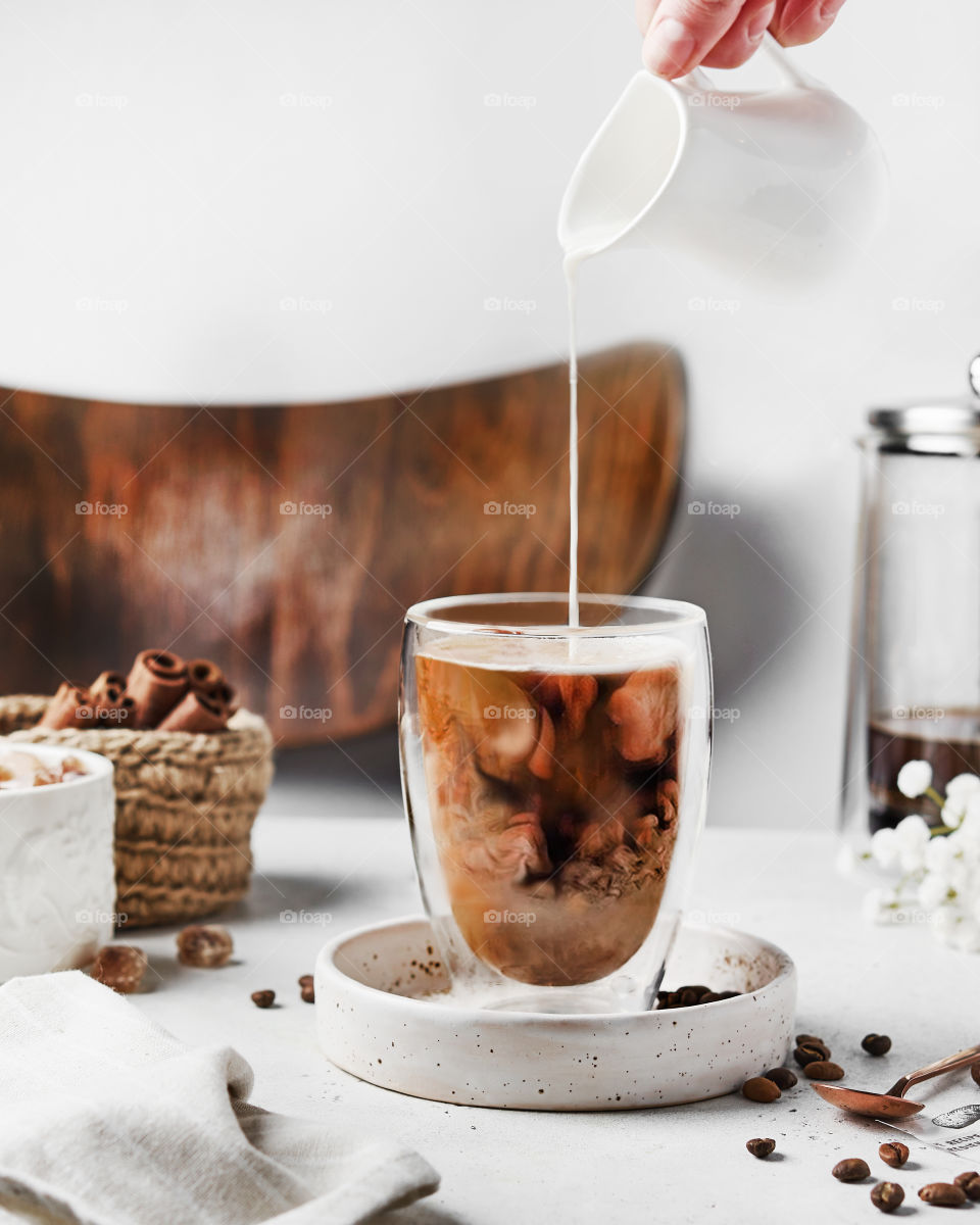 Pouring milk into a glass of coffee