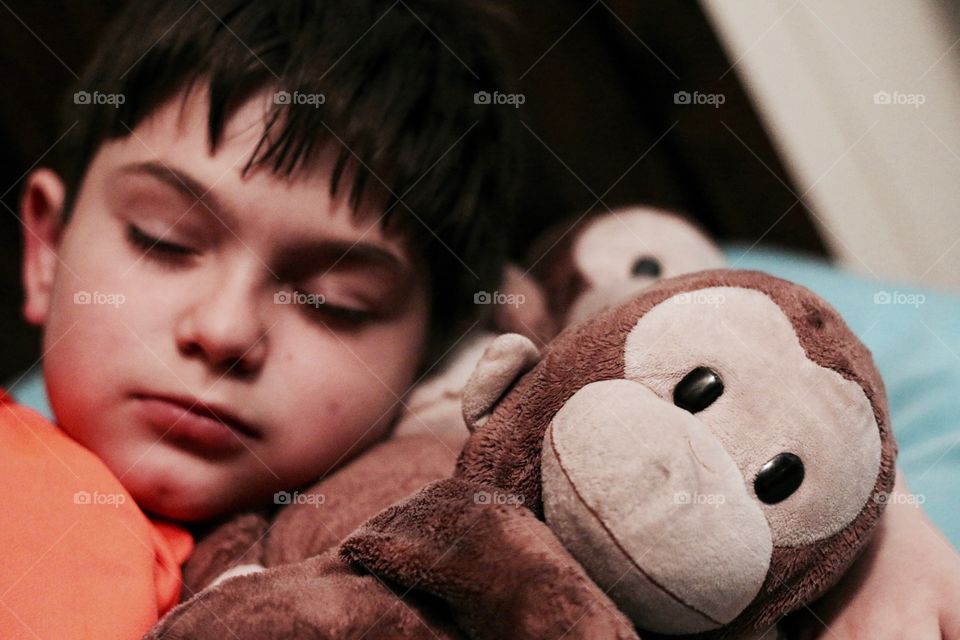 Child snuggling with his monkey while he sleeps