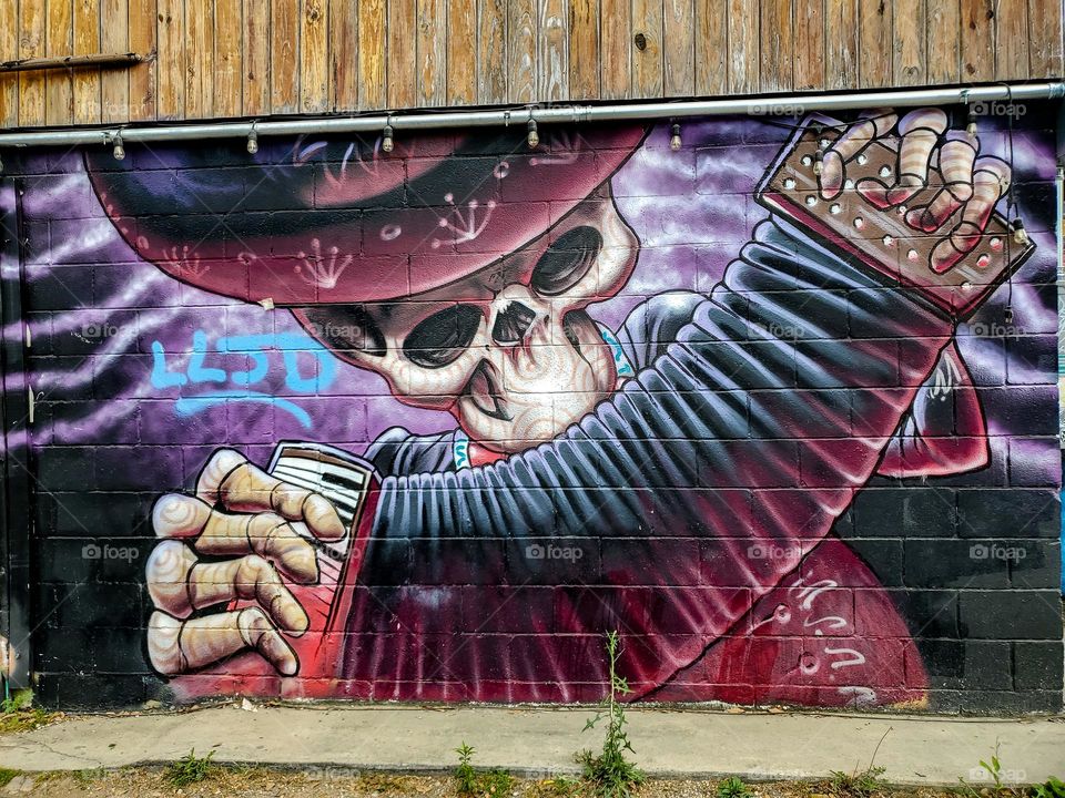 Street art celebrating Dia de los muertos. A Mexican cultural tradition of celebrating the dead.  In this piece there is a dead musician playing the accordion.