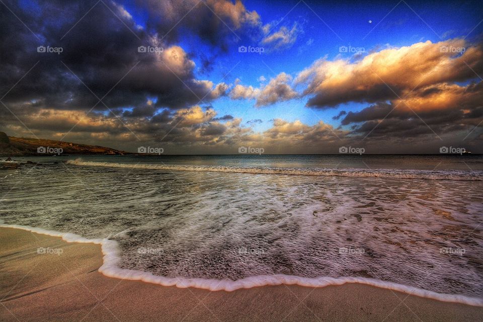 Surf's Up. A wave breaks gently on the shore of a sandy beach at sunrise.