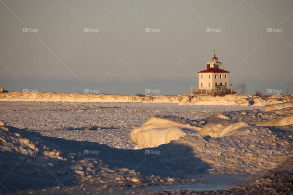 Sun shines on the Fairport Harbor West Breakwater Lighthouse in Winter showing red color effect and rule of thirds in photography 