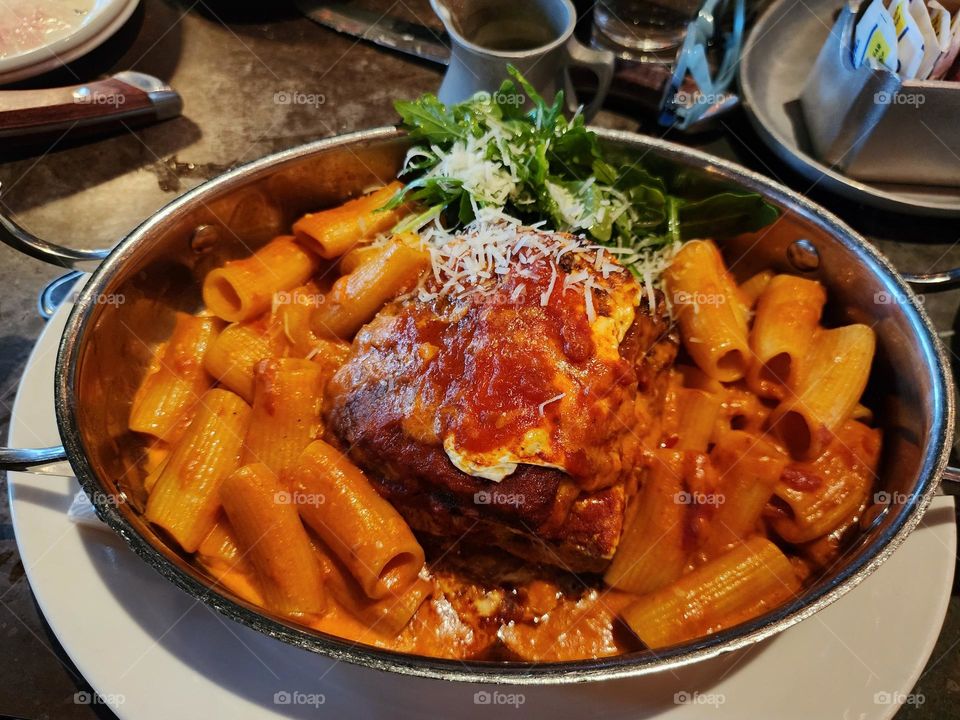 large plate of baked ziti and eggplant parmesan. Top with mozzarella, fresh basil, and parmesan cheese.