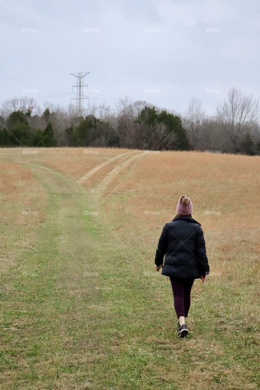 An athletically dressed woman walks a country hillside in Mount Juliet, Tennessee 