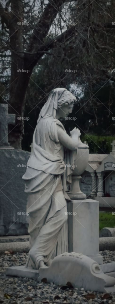 at Mission Cemetery an old gravesite with the greek statue watching over the deceased