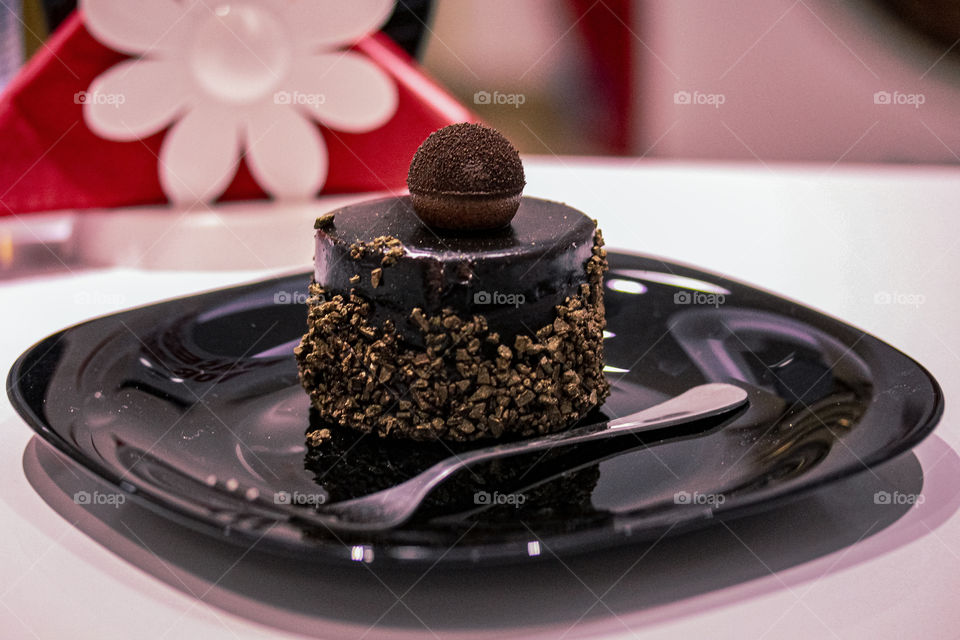 chocolate cake with walnuts on a black plate