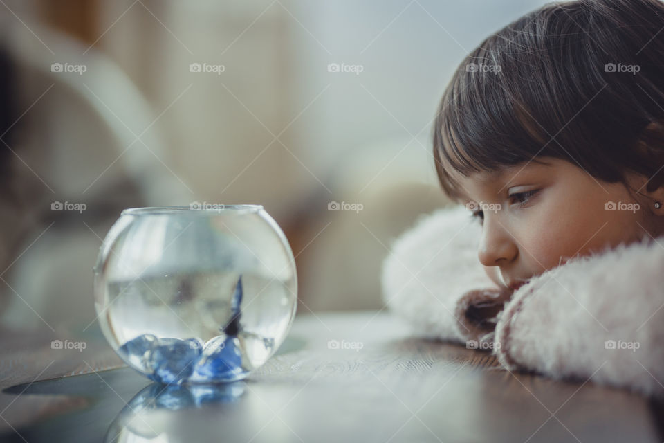 Girl with fish in round aquarium.