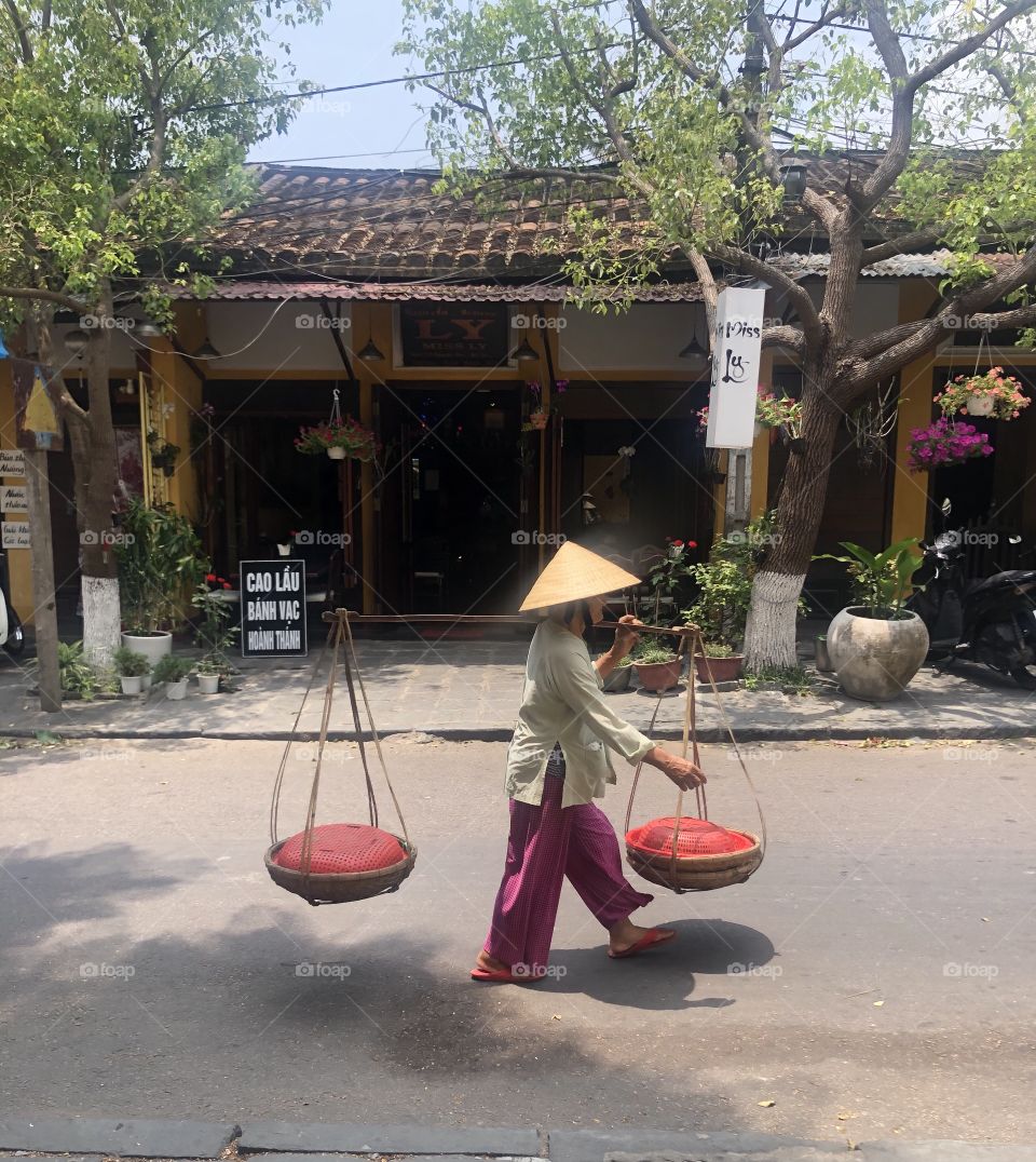 Old women yoke goods after a market meeting in Hoi An Đà Nẵng (she's wearing palm-leaf conical hat)