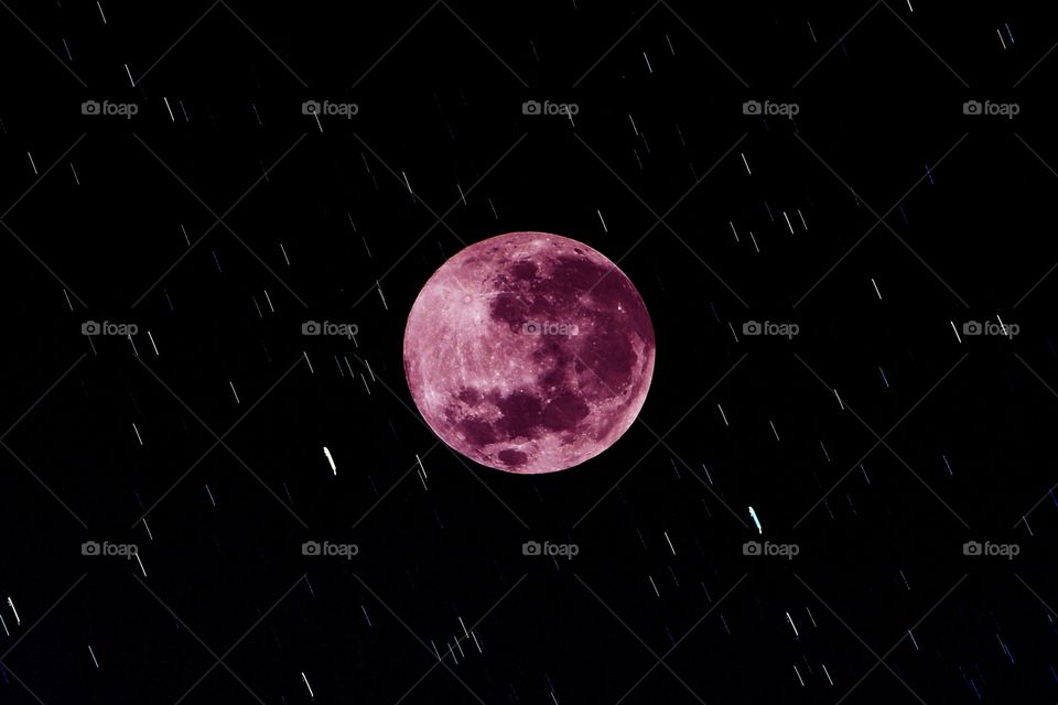 The pink supermoon of April 26, 2021 lights up the night with a  time exposed star studded space sky.