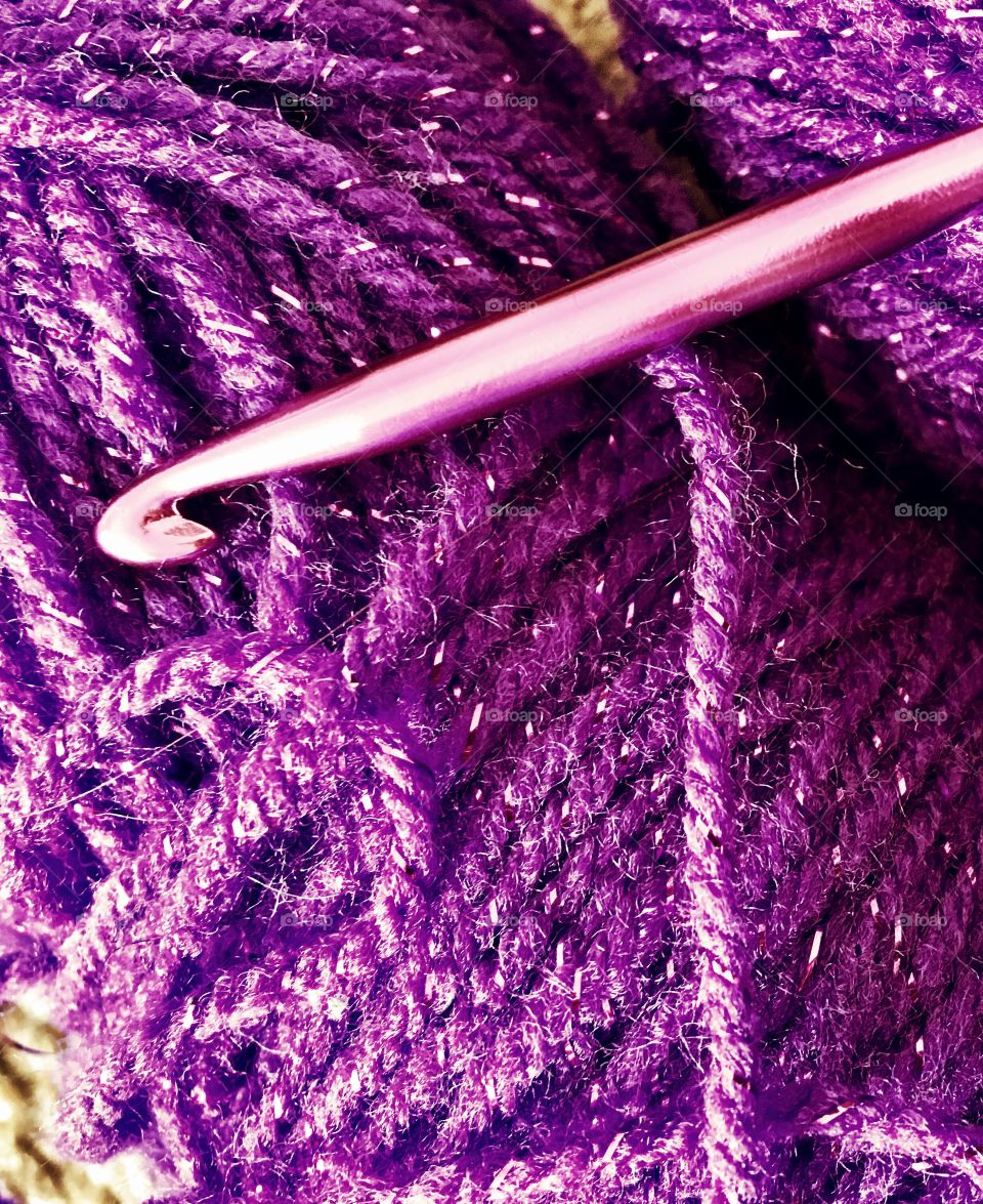 Close up of purple sparkle yarn and purple crochet hook