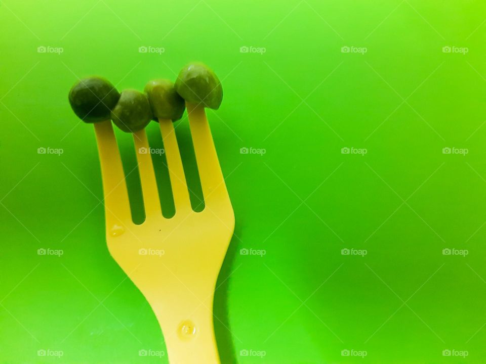 Yellow fork of green peas in green background