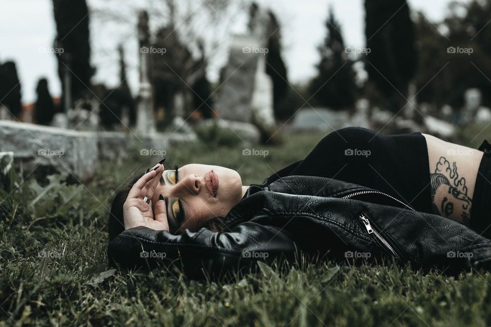 Girl lays in grass. She feels upset and closes her eyes