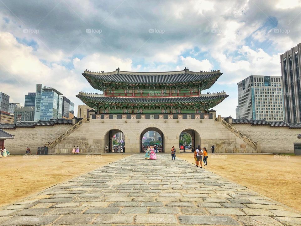 Gate of Korean palace ground with people wearing traditional clothing.