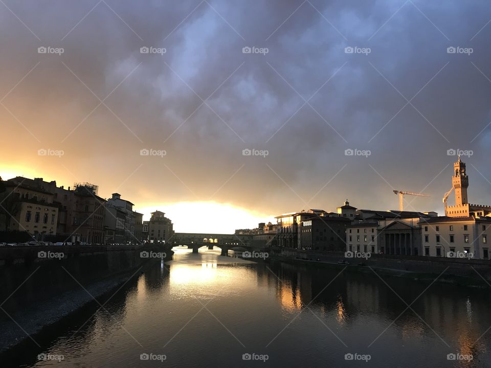 Rays of the evening sun beaming out from behind the ponte vecchio and reflecting off the Arno river in Florence, Italy.