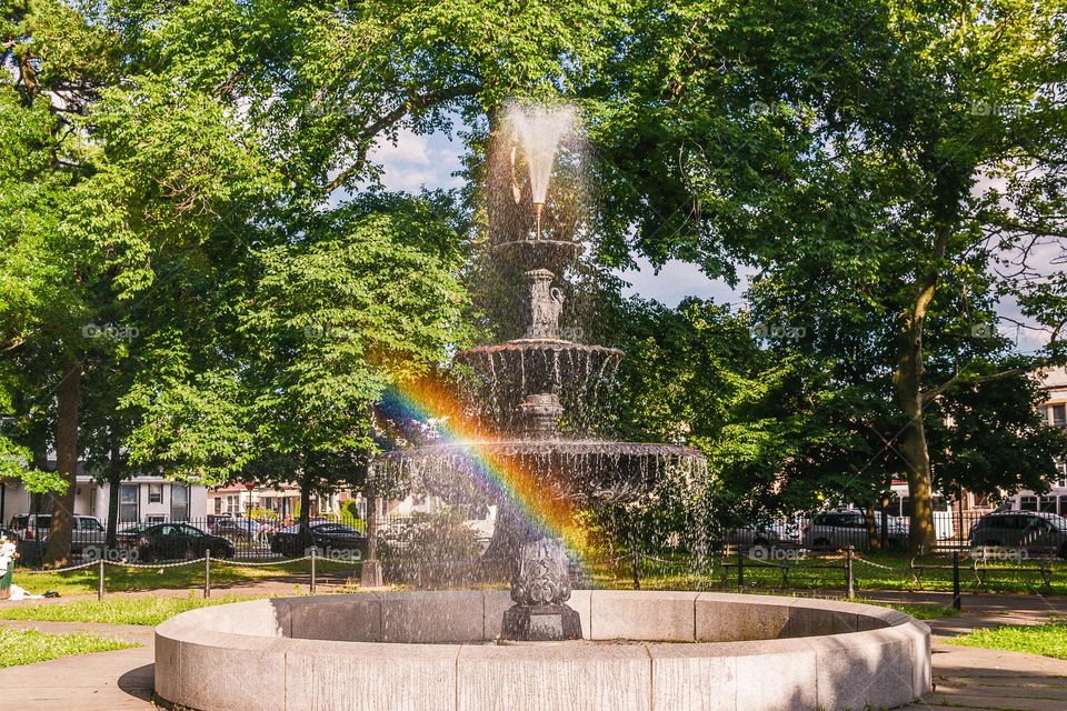 summer fountain with rainbow in the park