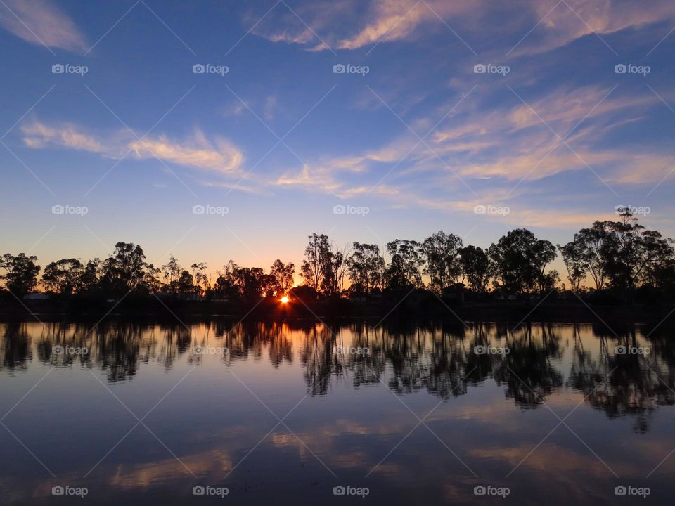 Skyline reflecting off a river at sunset.