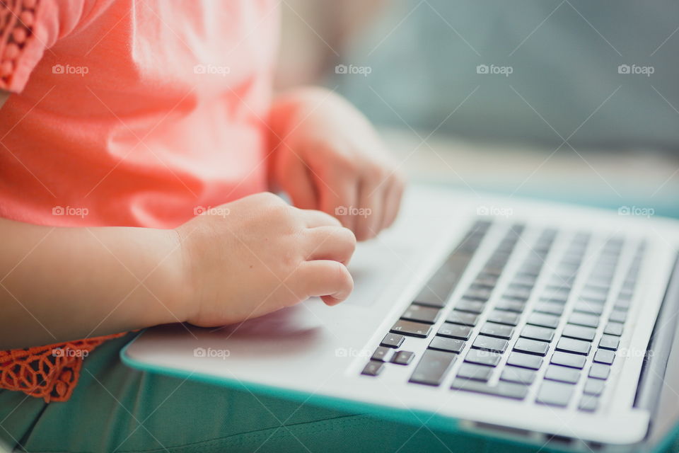 Little girl with gadgets(laptop and tablet) in the bed.