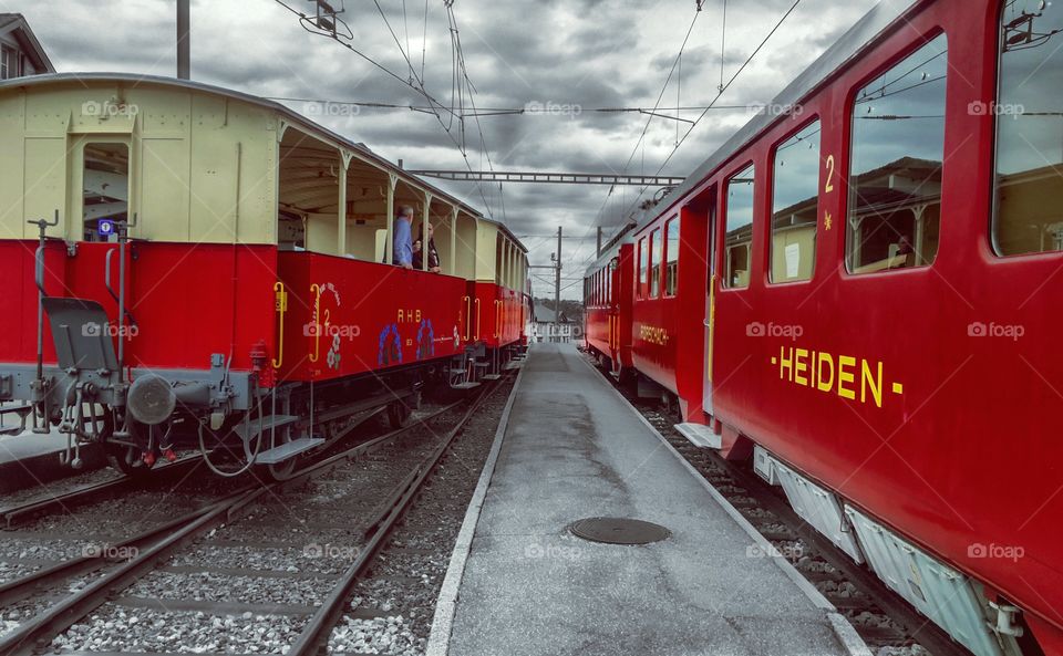 The red Heiden-Rorschach railway in the east of Switzerland on a cloudy day

