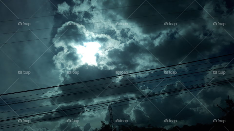 Sol por de trás de nuvens com efeito azulado do insufilme do carro.