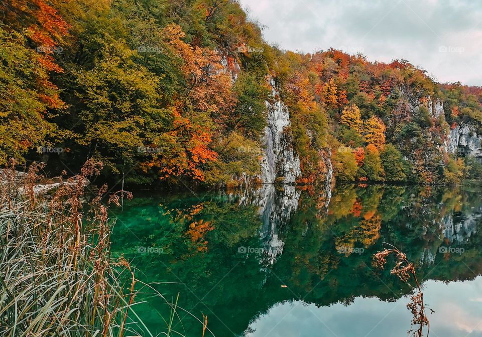 Beautiful autumn landscape with lush forest reflected in green lake at Plitvice lakes national park in Croatia
