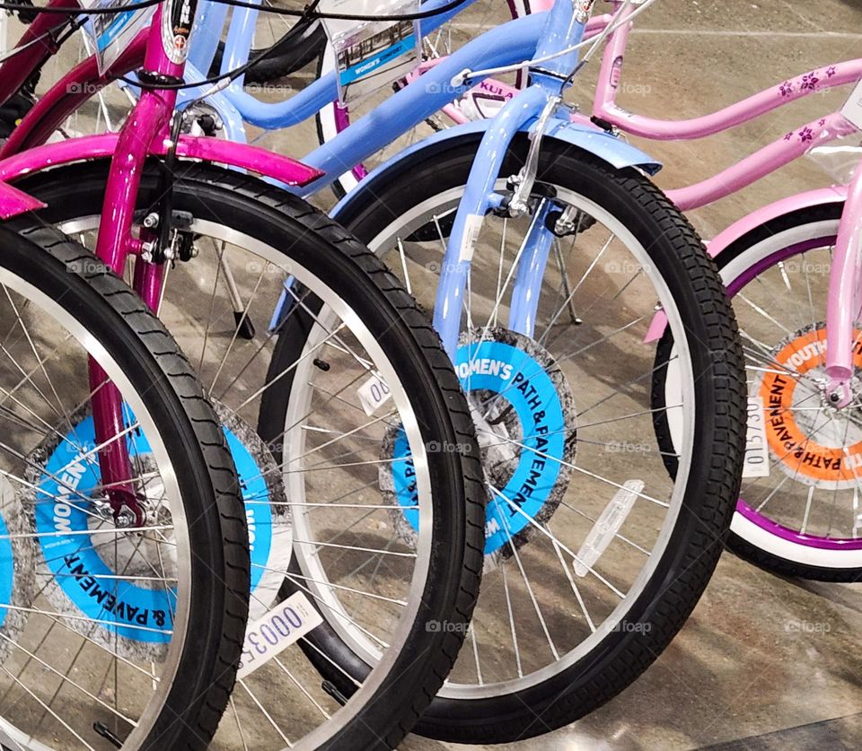 bright pink, blue, and purple youth mountain bikes lined up for sale in a sporting goods store